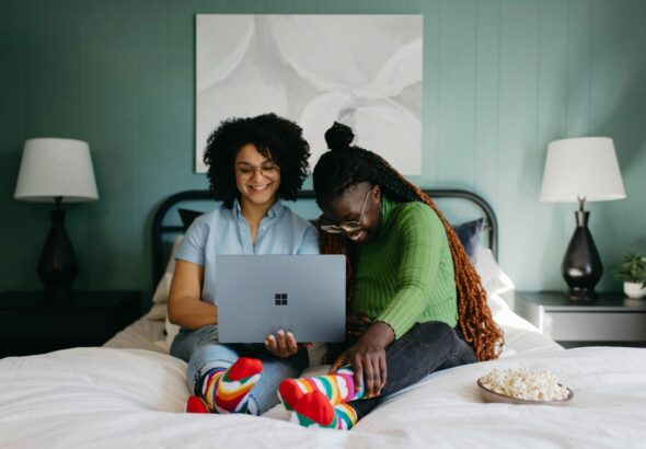 a woman sitting on a bed using a laptop