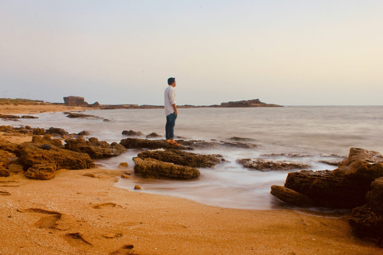 man in white shirt standing on brown sand near body of water during daytime: personal growth