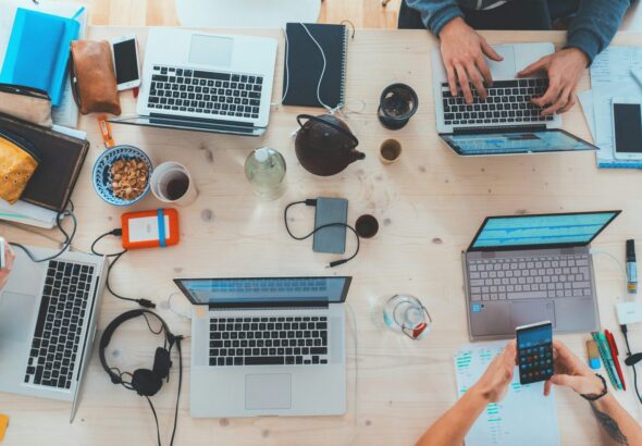 people sitting down near table with assorted laptop computers