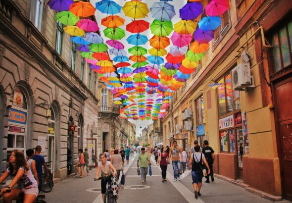 assorted-color umbrella hanged above pathway near houses