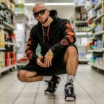 man squatting on floor between grocery items