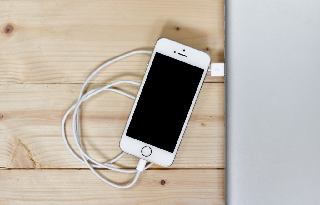 Charging a smartphone on a bedside table, with the phone placed at a safe distance from the bed, emphasizing the importance of minimizing phone radiation exposure during charging