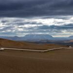 a dirt field with mountains in the background