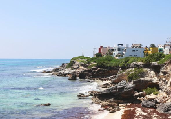 a view of a beach with houses on the cliff