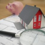 white and red wooden house beside grey framed magnifying glass