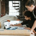 a man and a woman are looking at a laptop