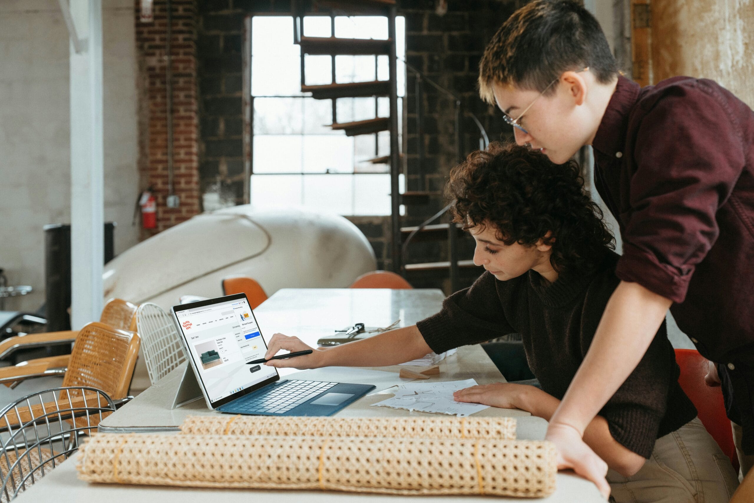 a man and a woman are looking at a laptop; How to Start Your Own Business Without Large Capital